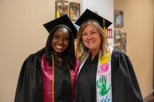 Two graduates posed in caps and gowns.