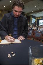 Student robed, then signs Freshmen Book