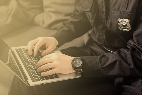 uniformed officer typing on laptop